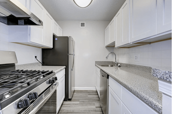 A kitchen with white cabinets and a stainless steel stove and refrigerator